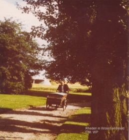 Ap Meeuwissen met bakfiets in park achter kerk 1985 achtergrond viaduct en N348 FB 23 mei 2016.jpg